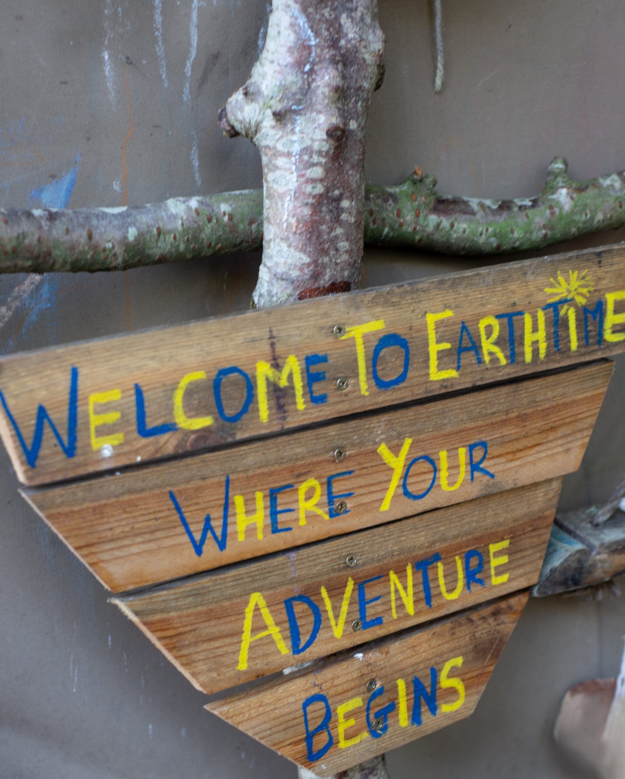 Wooden sign which reads Welcome to Earthtime where your adventure awaits.